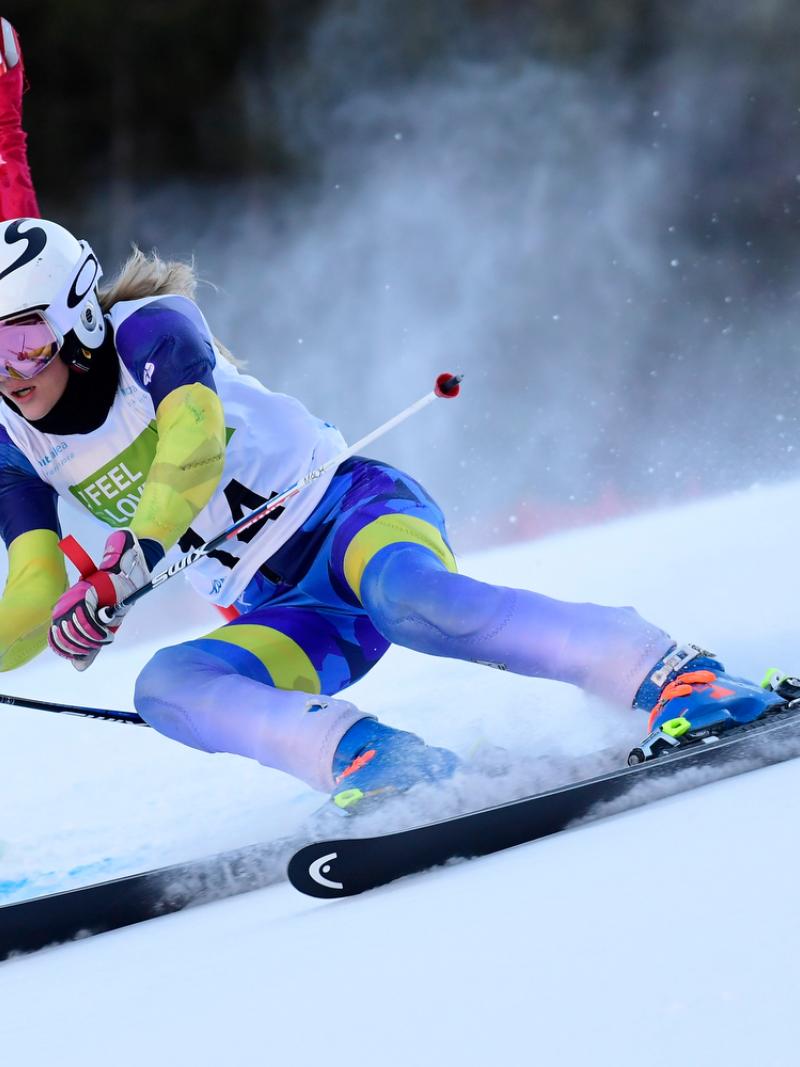 A female Para alpine skier crossing a pole in a slalom event