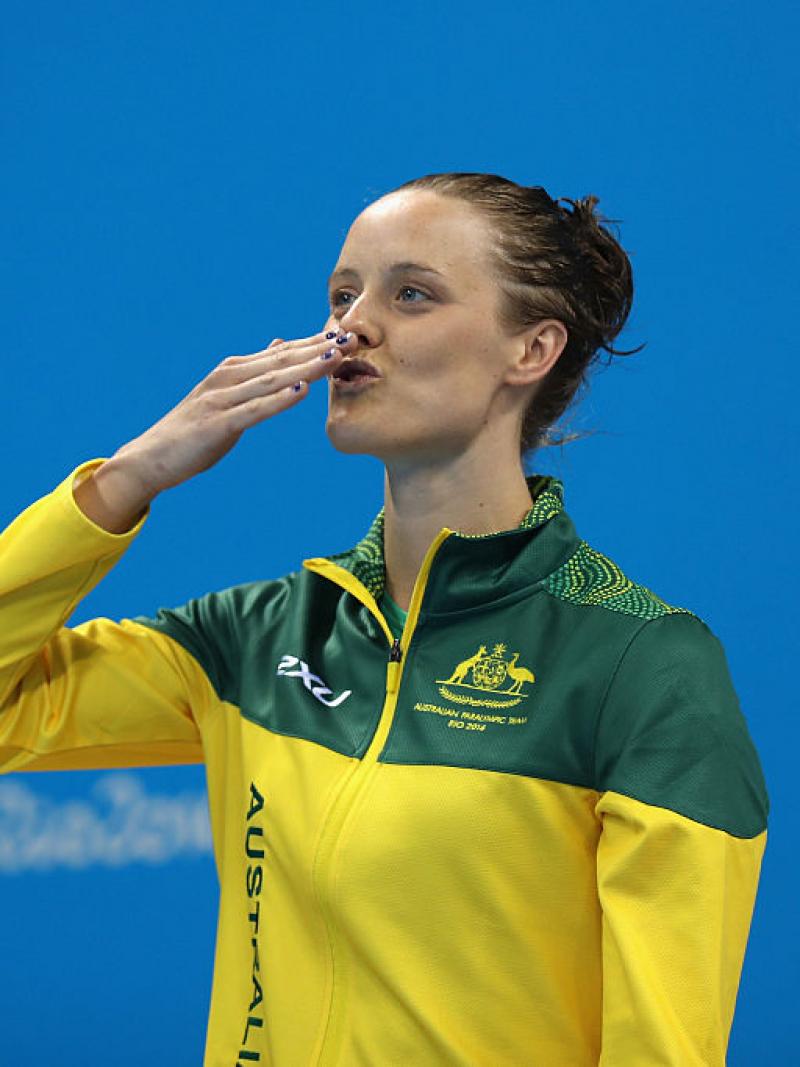 A woman sending a kiss to the audience while standing on the podium waiting to receive a medal
