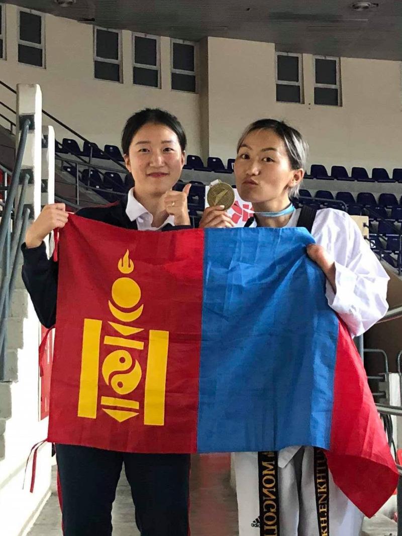 Female taekwondo athlete hold Mongolian flag with friend and her medal