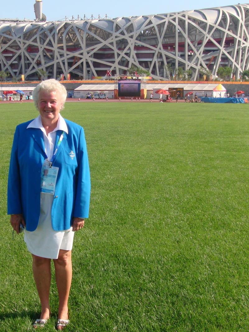 A woman in white skirt and blue jacket posing in front of the athletics stadium during the Beijing 2008 Paralympics