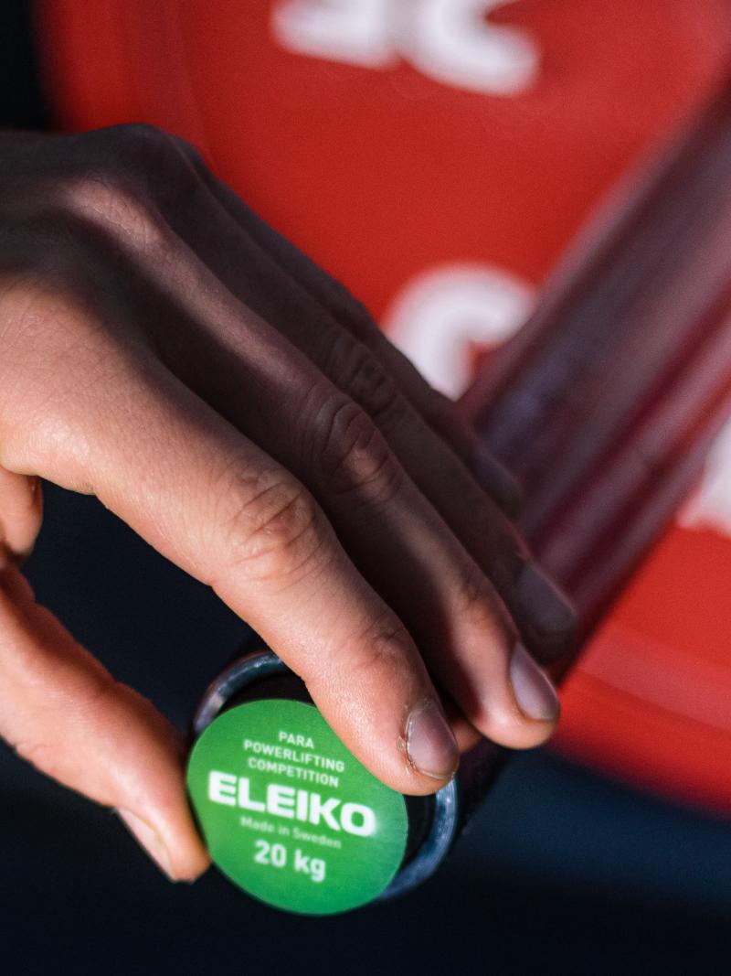 A male hand plugging a green Eleiko sensor on a barbell 