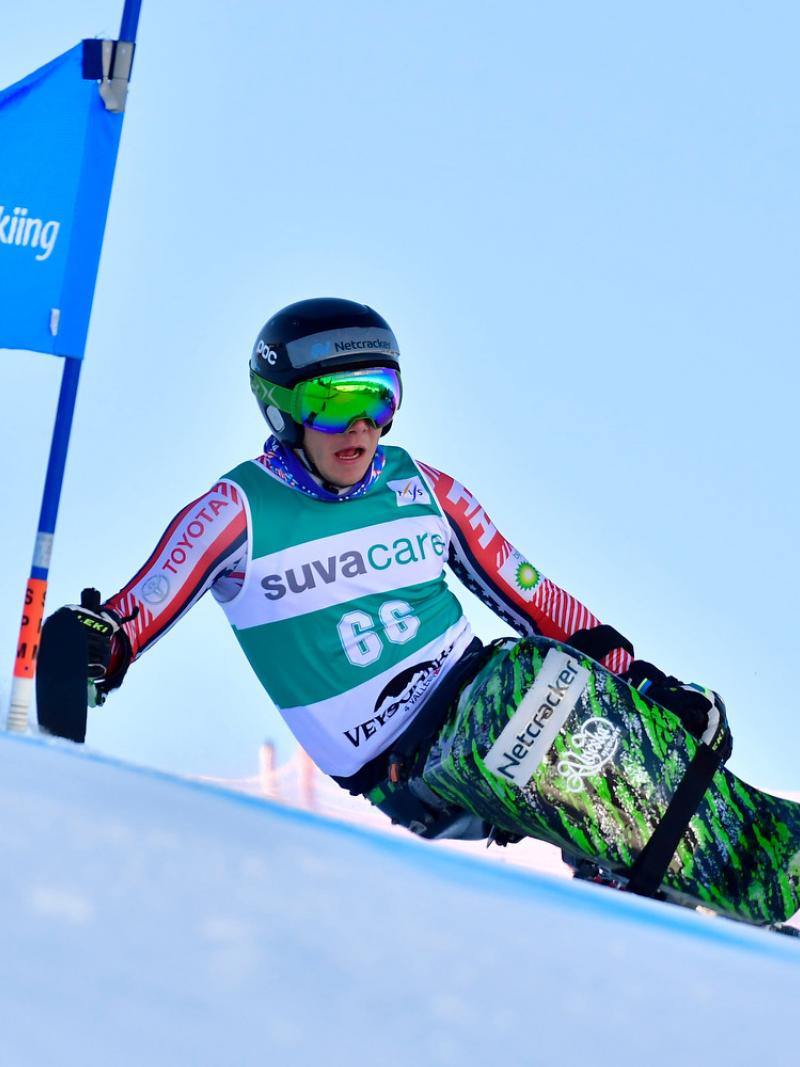 A male sit-skier competing in a Para alpine skiing giant slalom race
