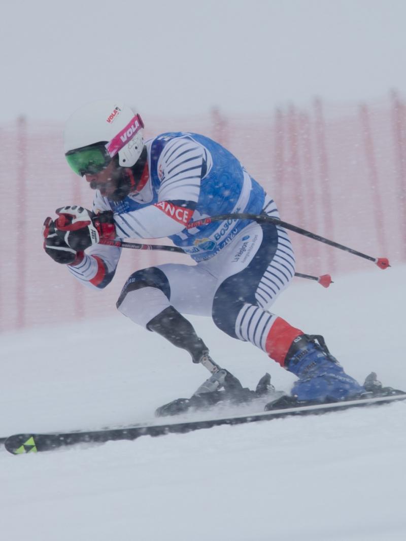 A men with a prosthetic leg skiing under heavy snow