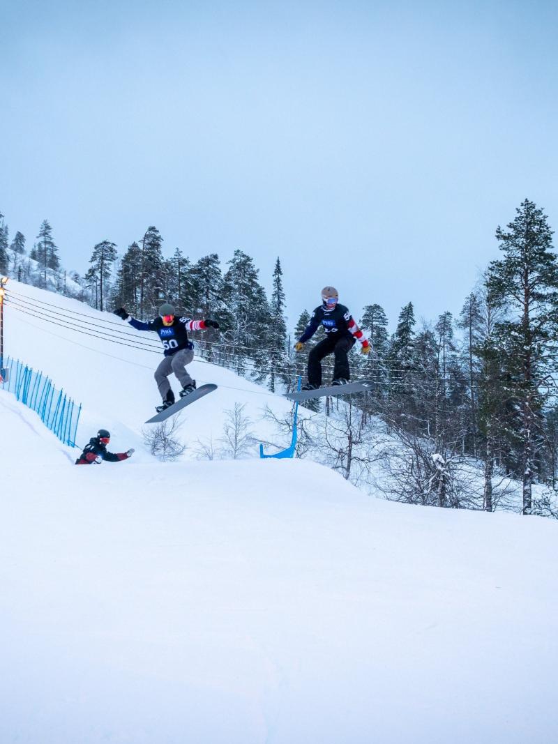 A group of male snowboarders jumping during a competition