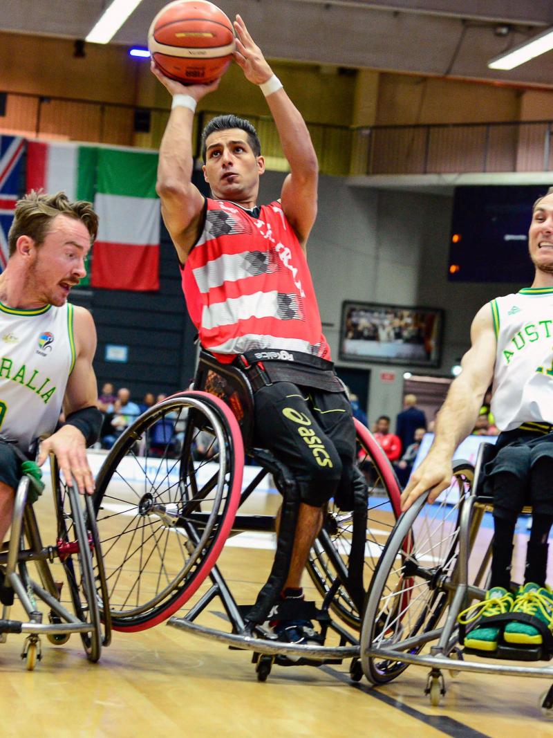 Two Australian men's wheelchair basketball players defend and Iranian athlete shooting the ball
