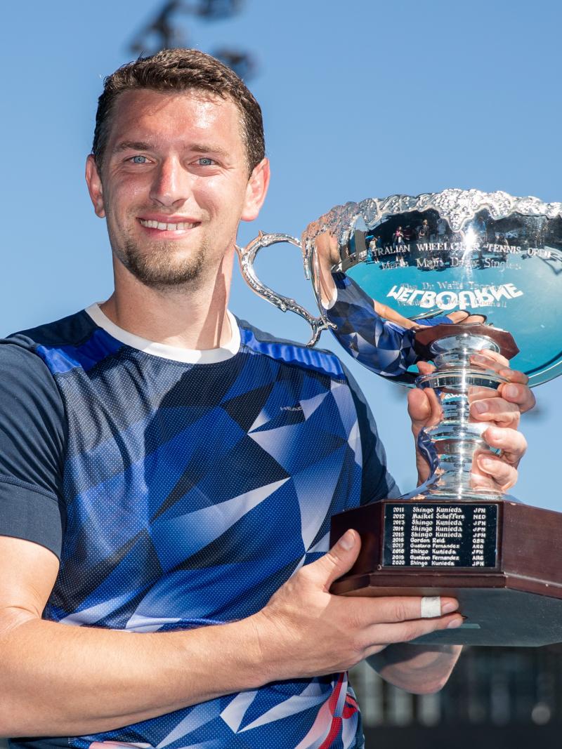 Belgian wheelchair tennis player smiles with Australian Open trophy