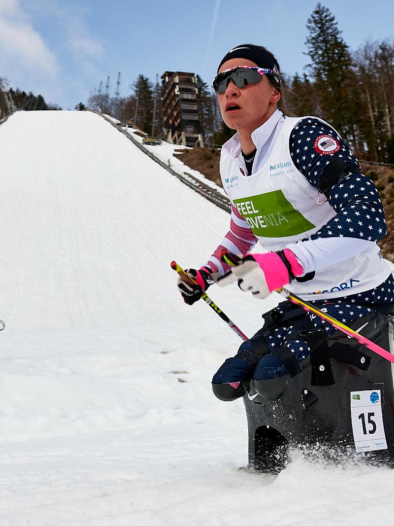 A female cross-country skier passing in front of a ski slope 