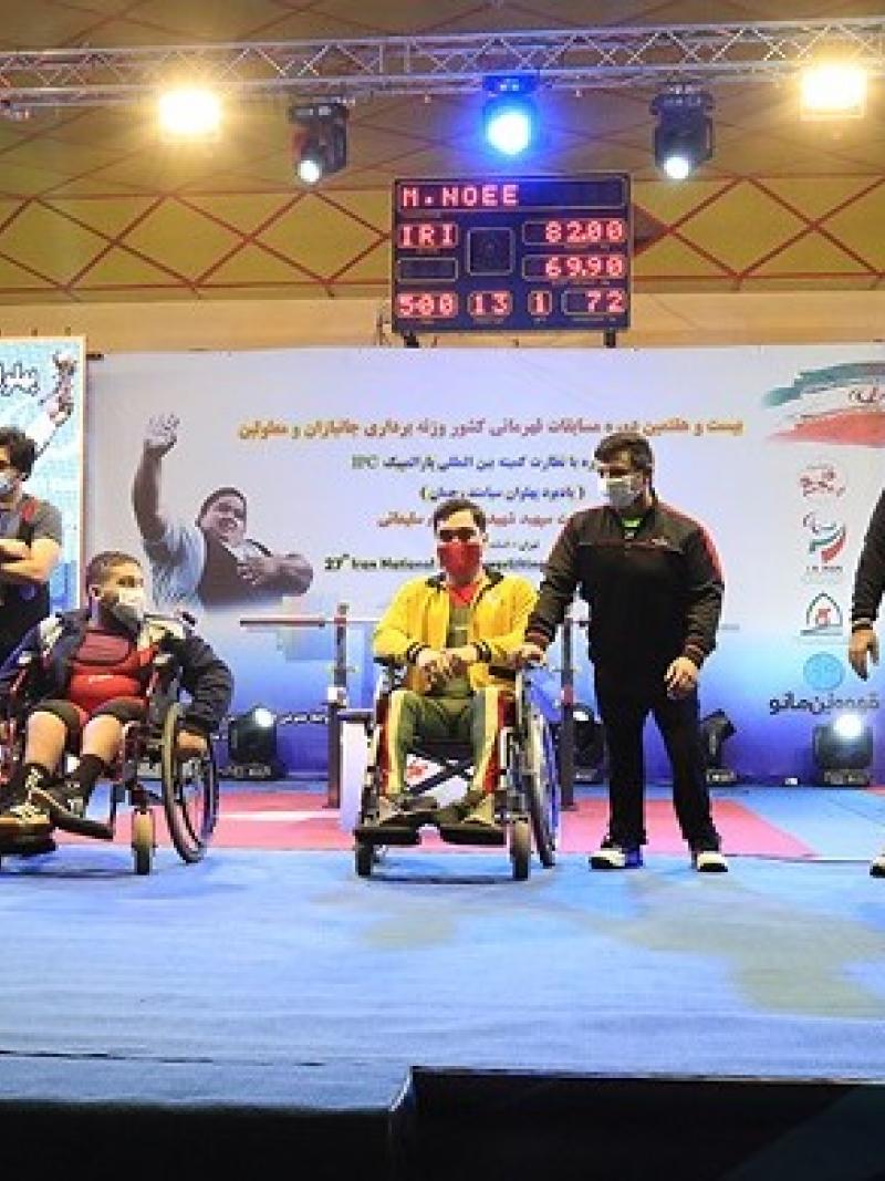 A group of three men in wheelchairs and five standing men on a stage