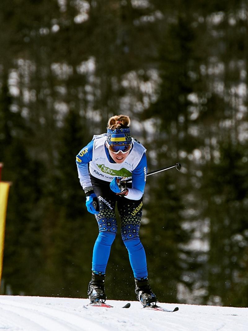 A female cross-country standing skier with a bandana with the Ukrainian flag competing in the snow
