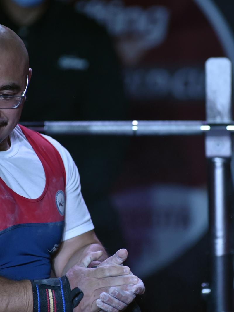 A man holding his hands on a bench press during a powerlifting competition