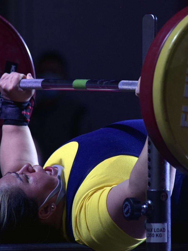 A woman lifting a bar on a bench press competition