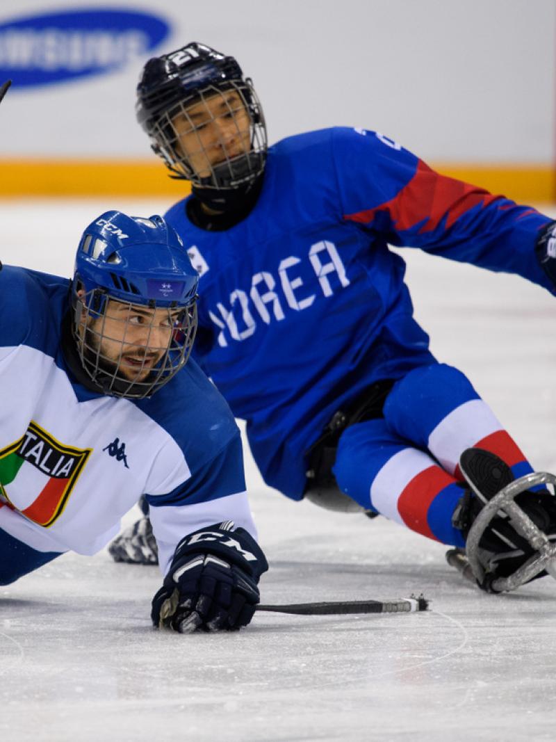 An Italian and a South Korea Para ice hockey player during a game on ice