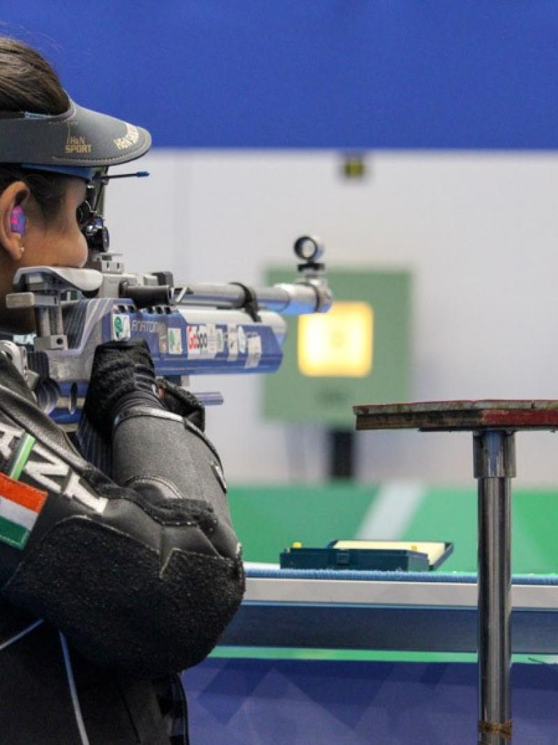 A woman shooting with a rifle in a shooting range seen from behind