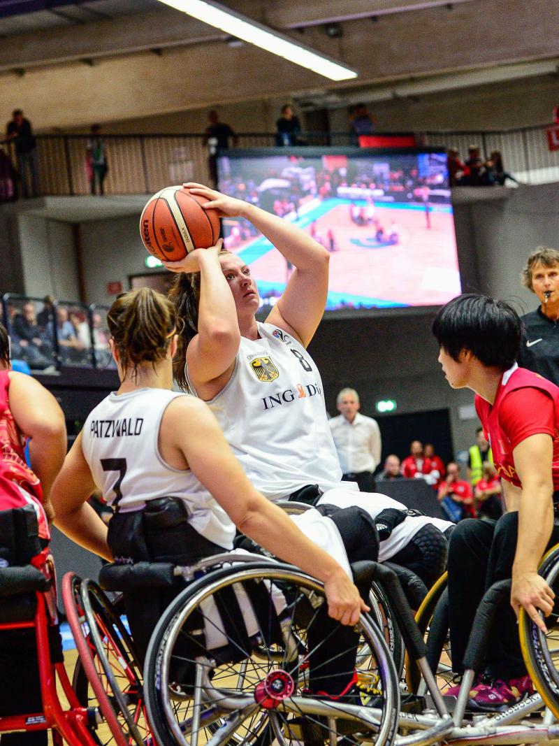 Woman shoots basketball over defenders