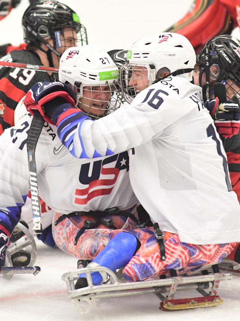 Two men in sledges celebrating with the USA uniform in a Para ice hockey game