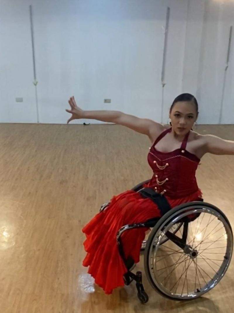 A woman in a wheelchair dancing in a room