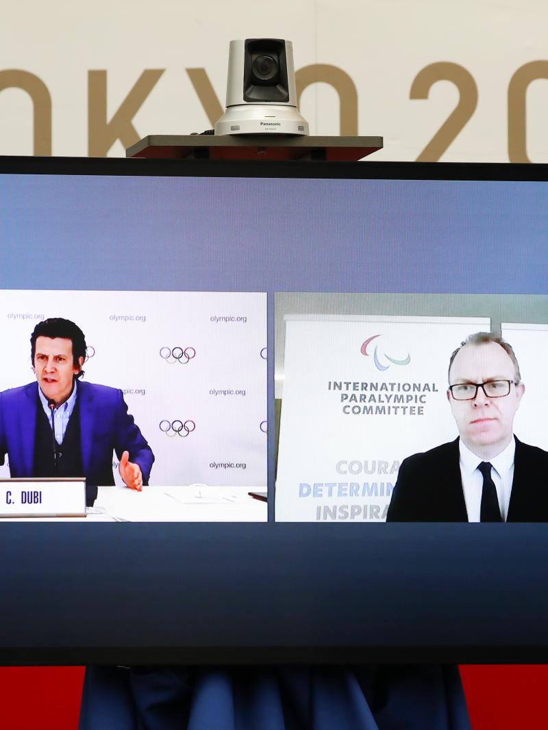 A monitor shows the IOC's Olympic Games Operations Director Pierre Ducrey and IPC's Chief Brand and Communications Officer Craig Spence participating remotely in the Tokyo 2020 Playbooks Press Briefing