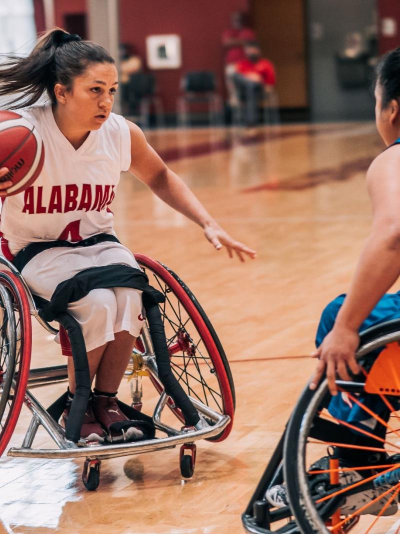 Woman playing wheelchair basketball tries to get around her defender