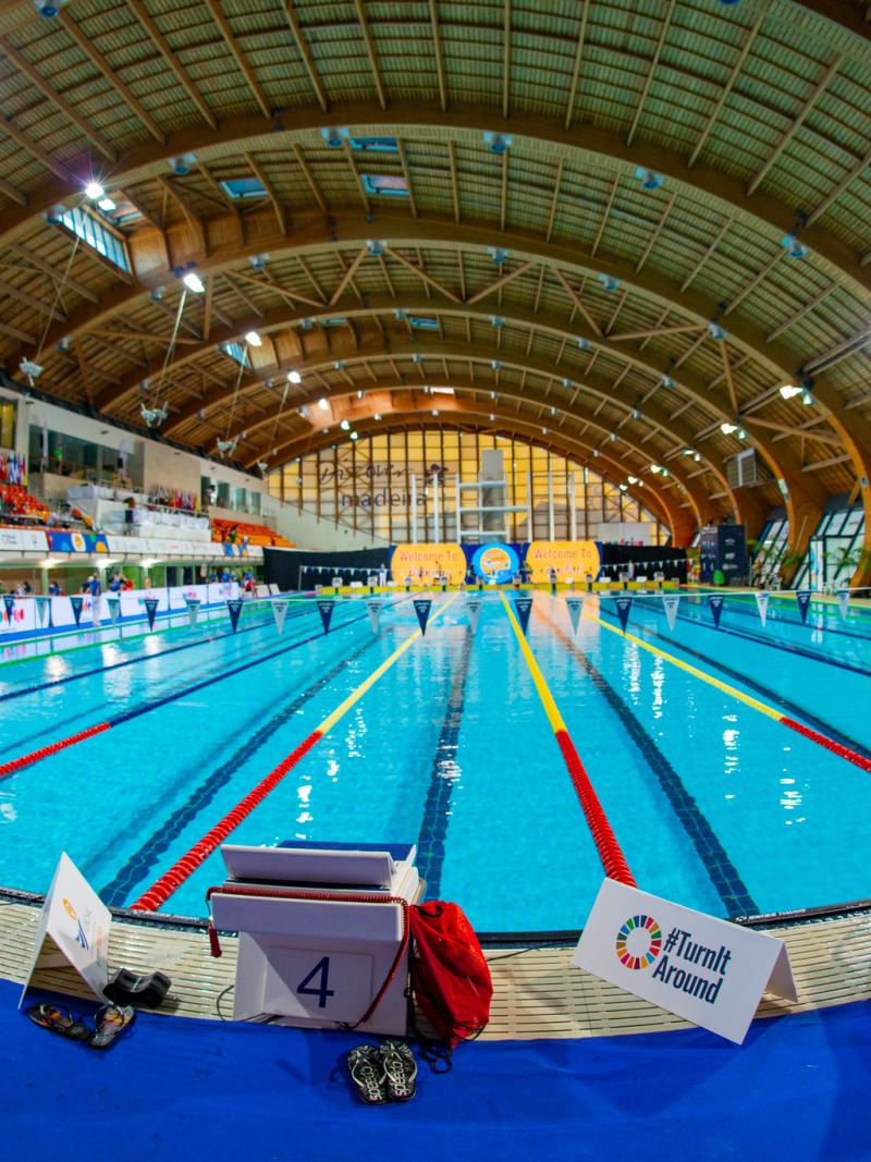 A indoor swimming pool with people watching in the stands