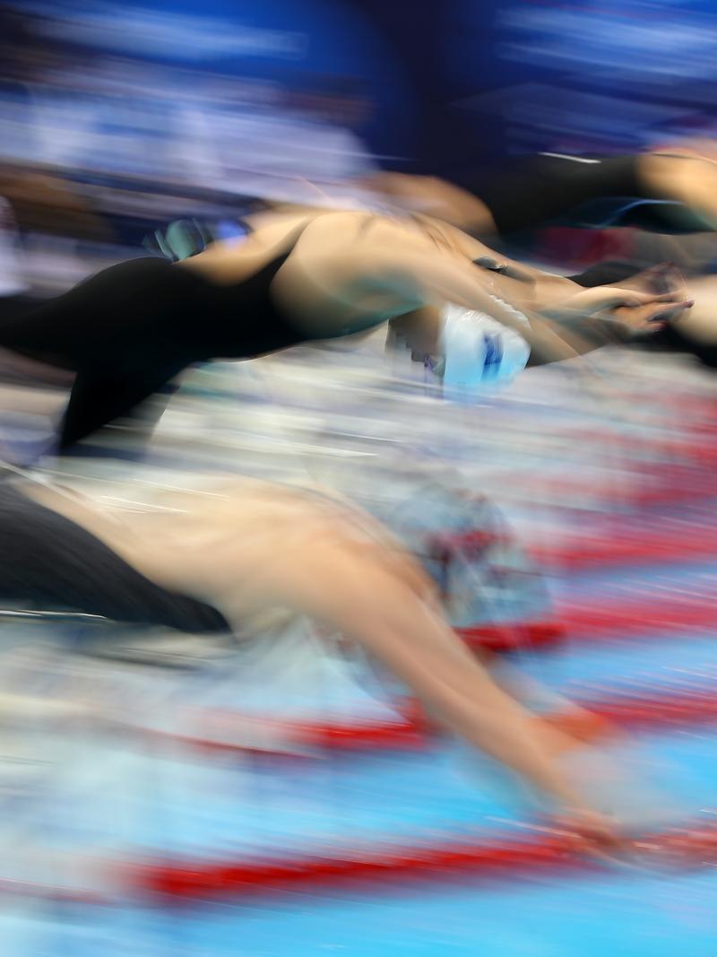 A blurred picture of a group of female swimmers jumping in the pool