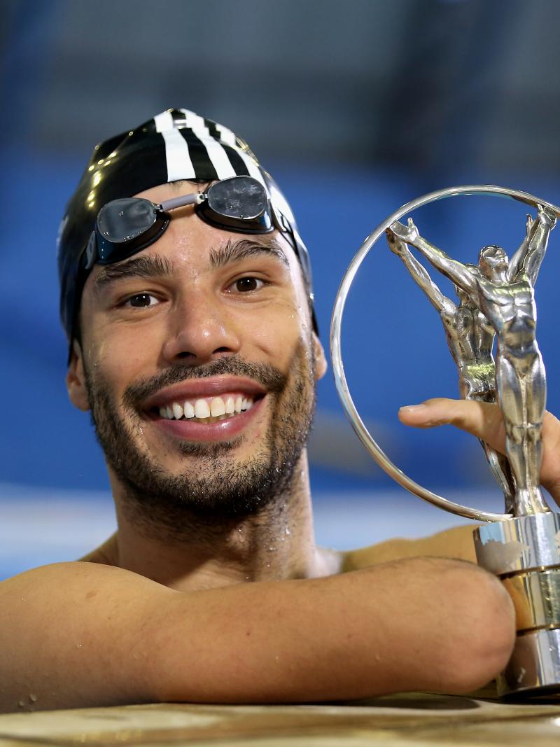 A man in a swimming pool posing with the Laureus Awards