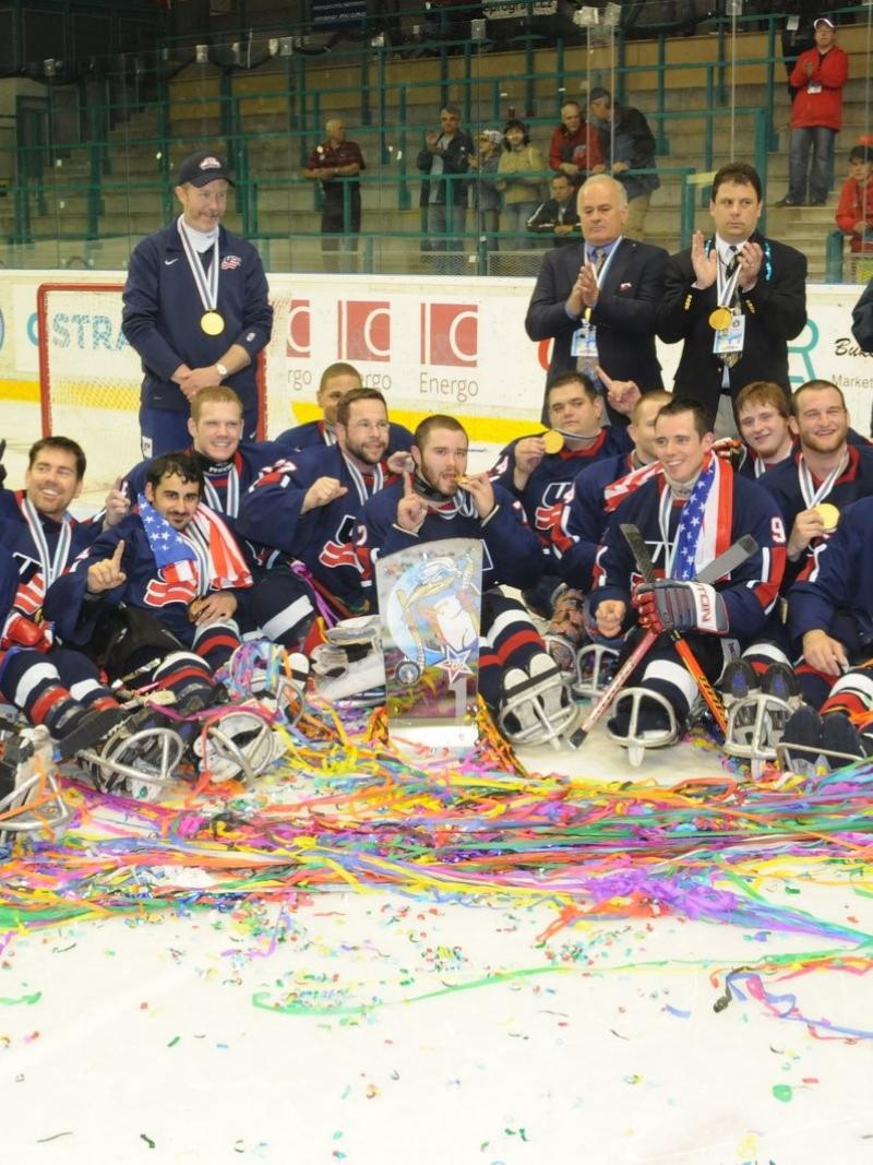 A group of Para ice hockey players with USA uniforms celebrating in an ice rink