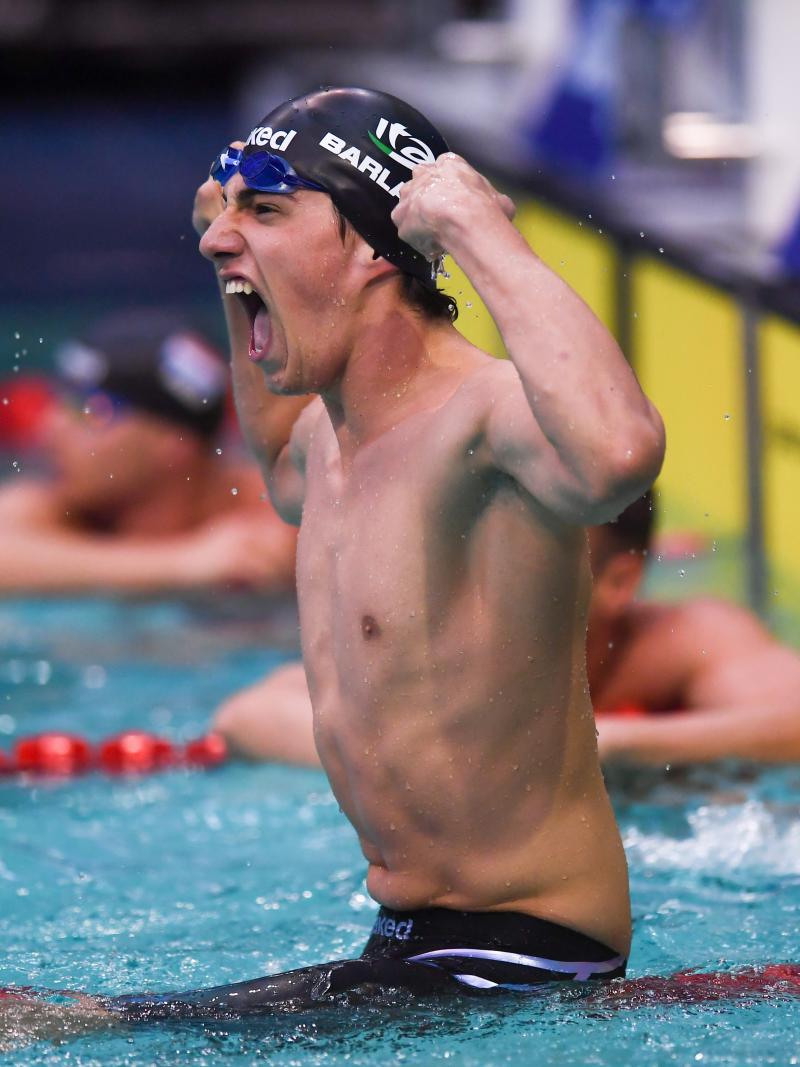 A swimmer celebrating in the pool observed by another swimmer