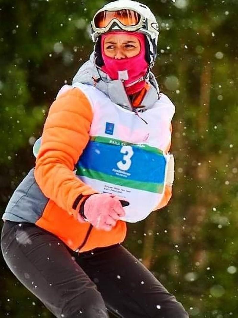 A female Para snowboarder riding with one arm