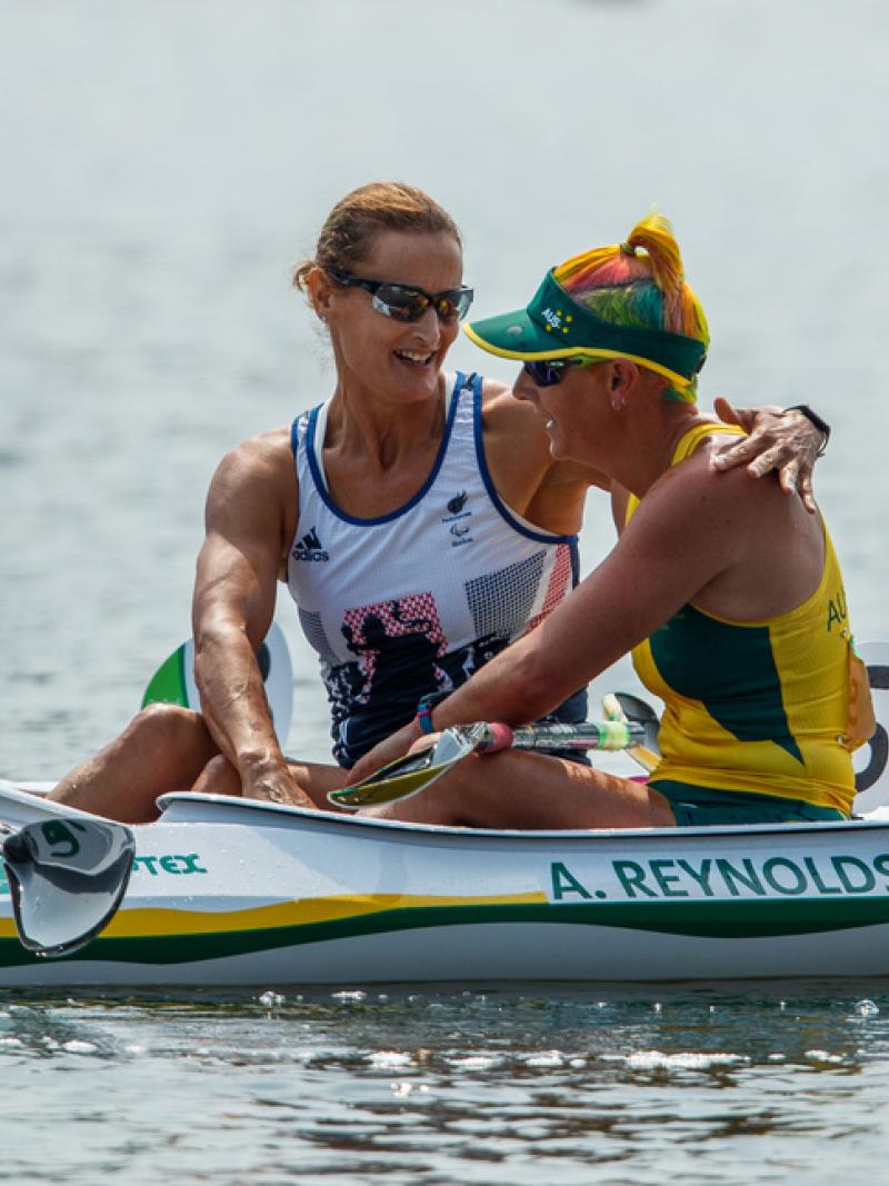 Two women in kayaks congratulate each other after a race