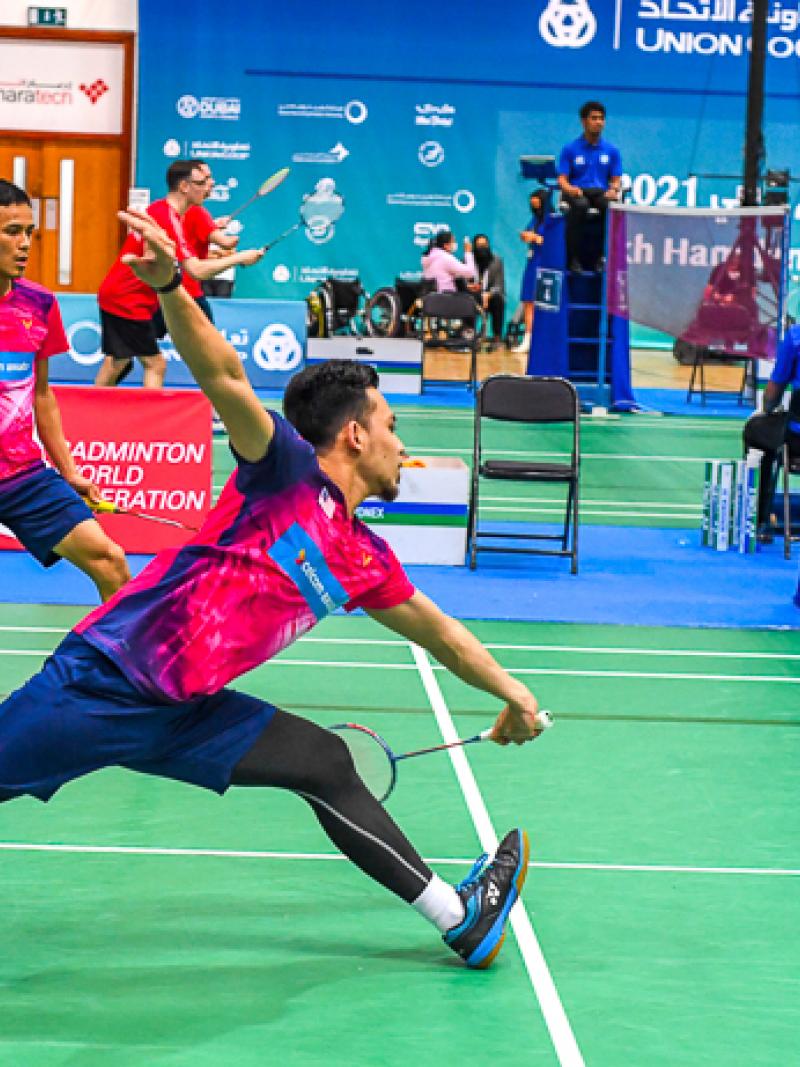 Male athlete reaches for the shuttle while competing in a males doubles team