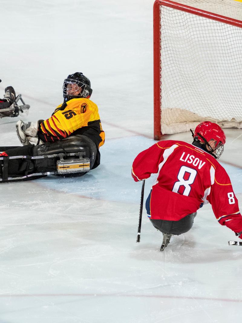 A Para ice hockey player scoring a goal observed by other four players