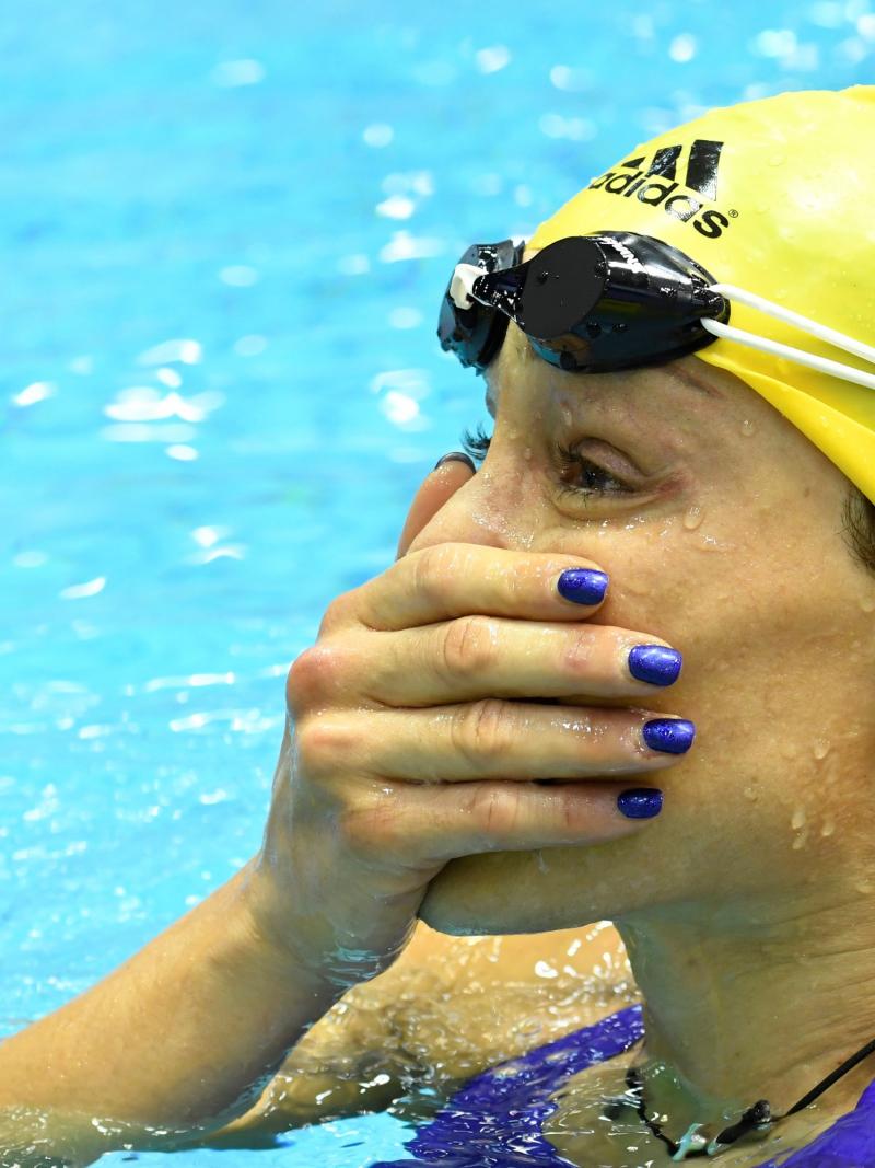 A woman in a swimming pool with a hand in her mouth as in surprise