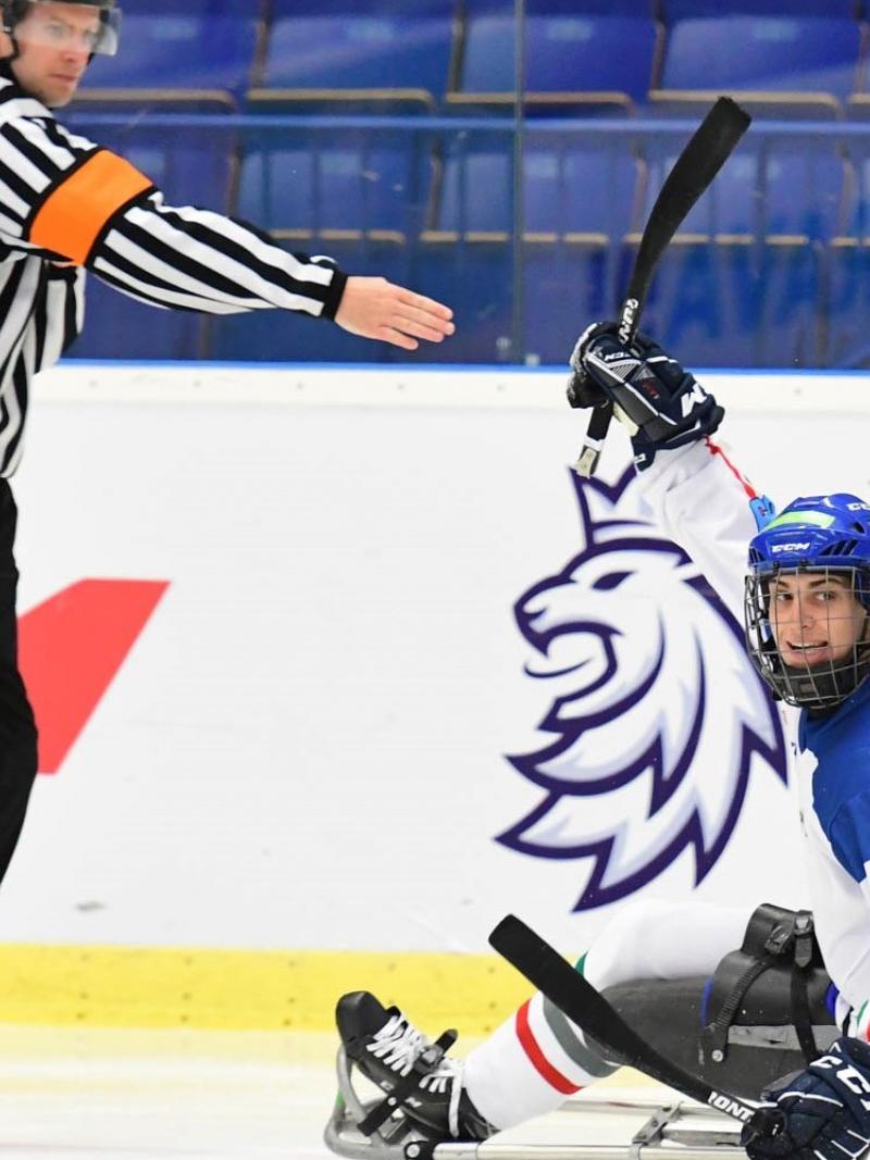 An ice hockey in sledges on an ice rink near a referee