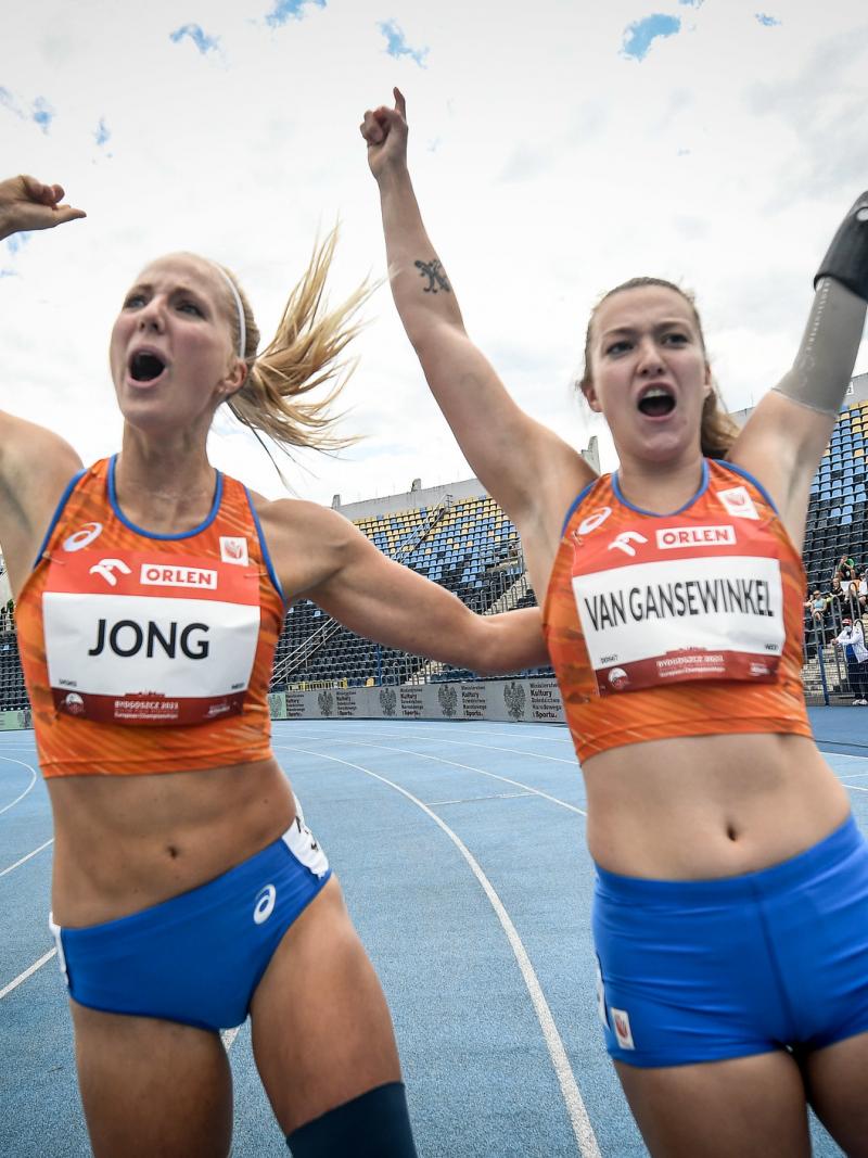 Two women with Netherlands uniform celebrating in a blue athletics track