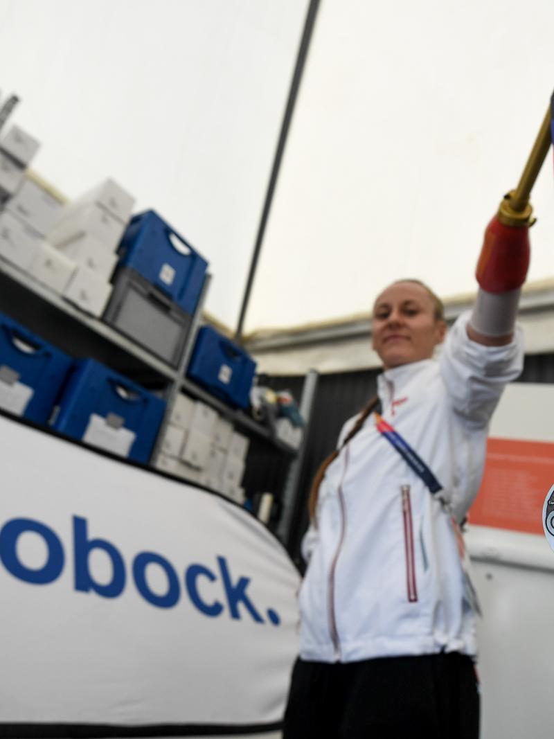 A woman with a prosthetic arm holding a silver medal