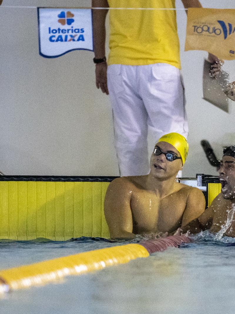 A male swimmer celebrating in the swimming pool next to another male swimmer