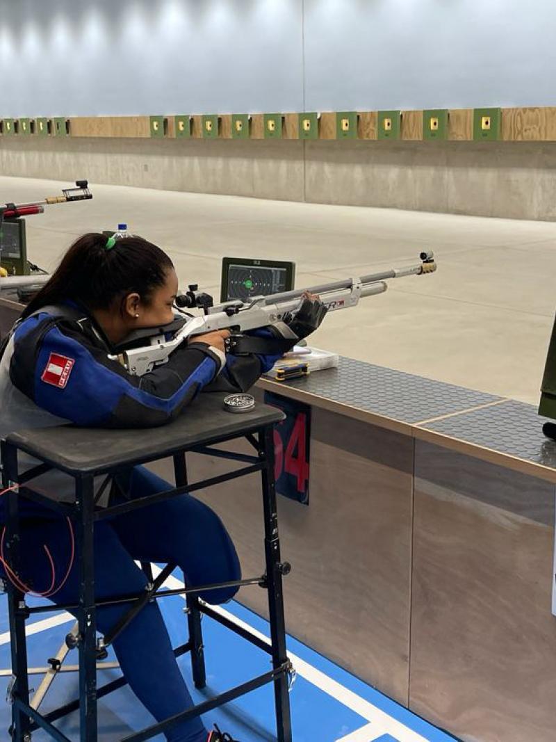 A female leg amputee and a men in a wheelchair practicing shooting in an indoor shooting range