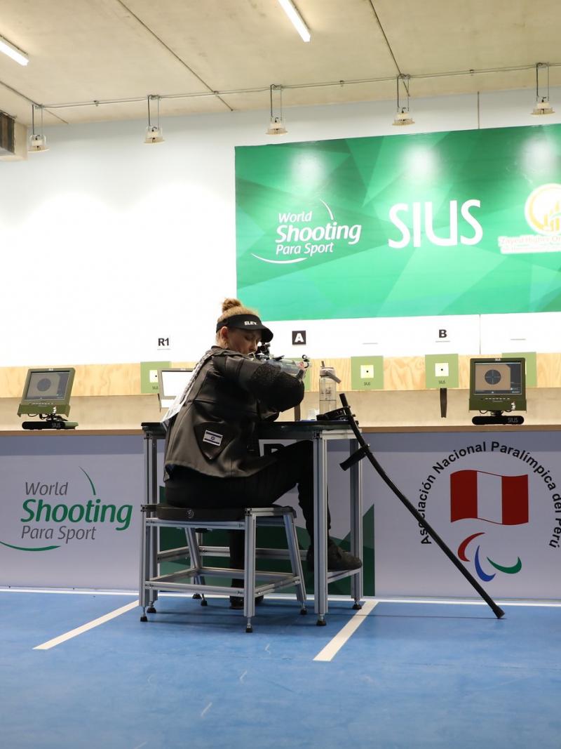 Three persons seated and shooting with rifles in a shooting range
