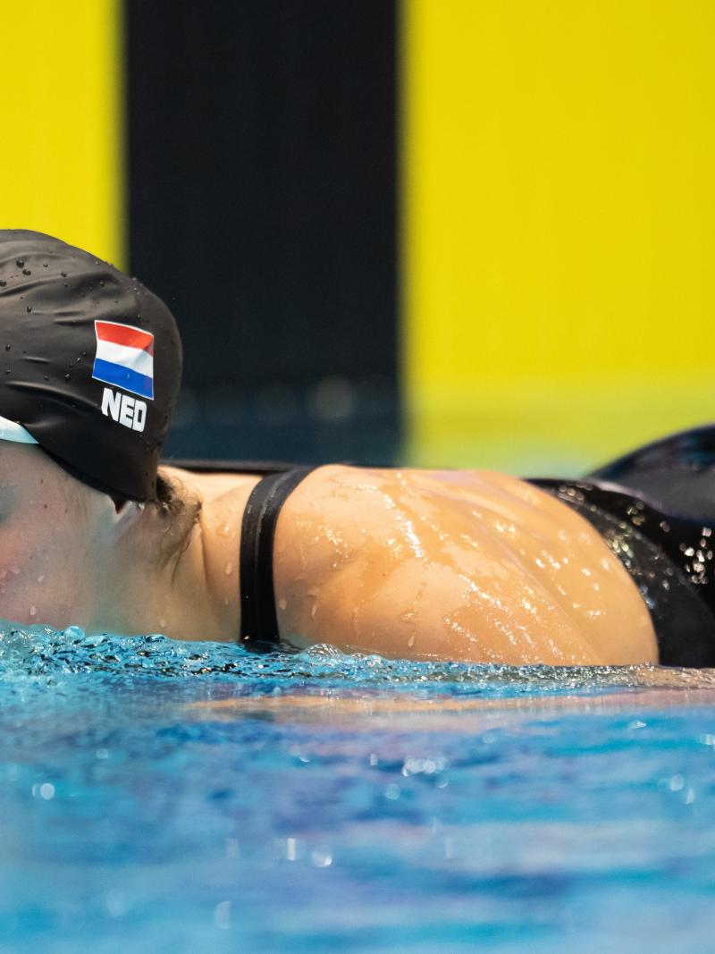 A woman with a black swimming cap putting her head out of the water
