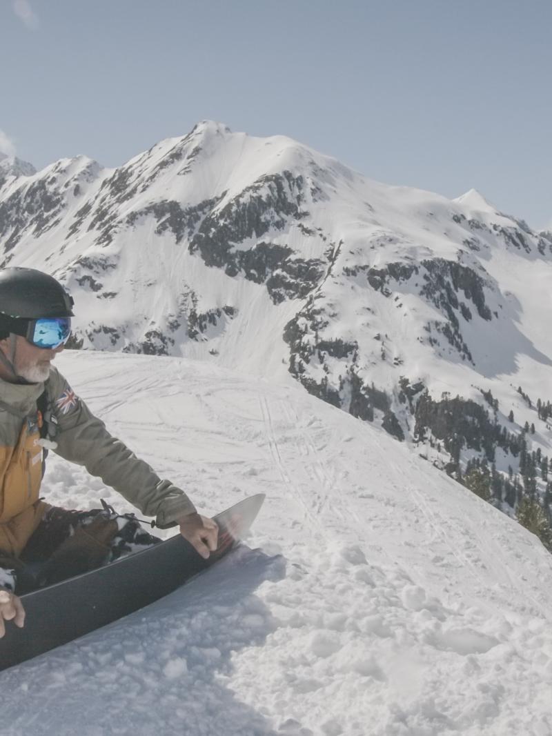 A male Para snowboarder watching the mountain