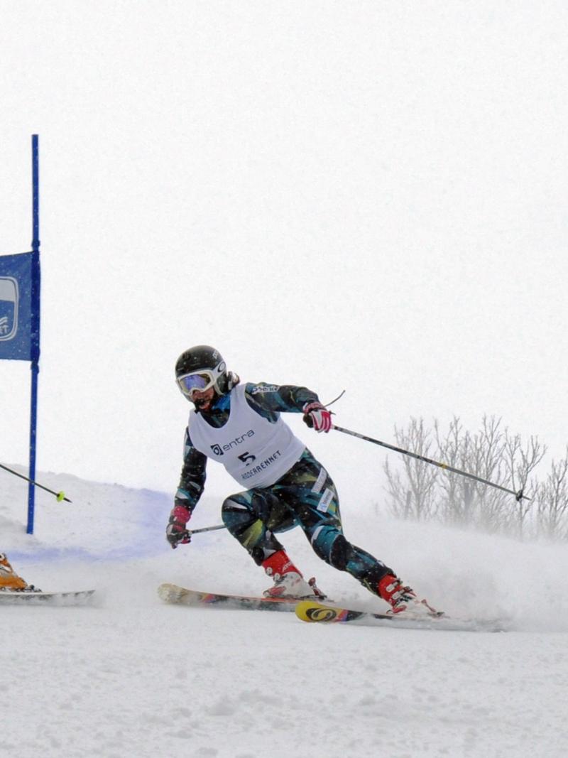 A female skier behind her guide in a Para alpine skiing competition