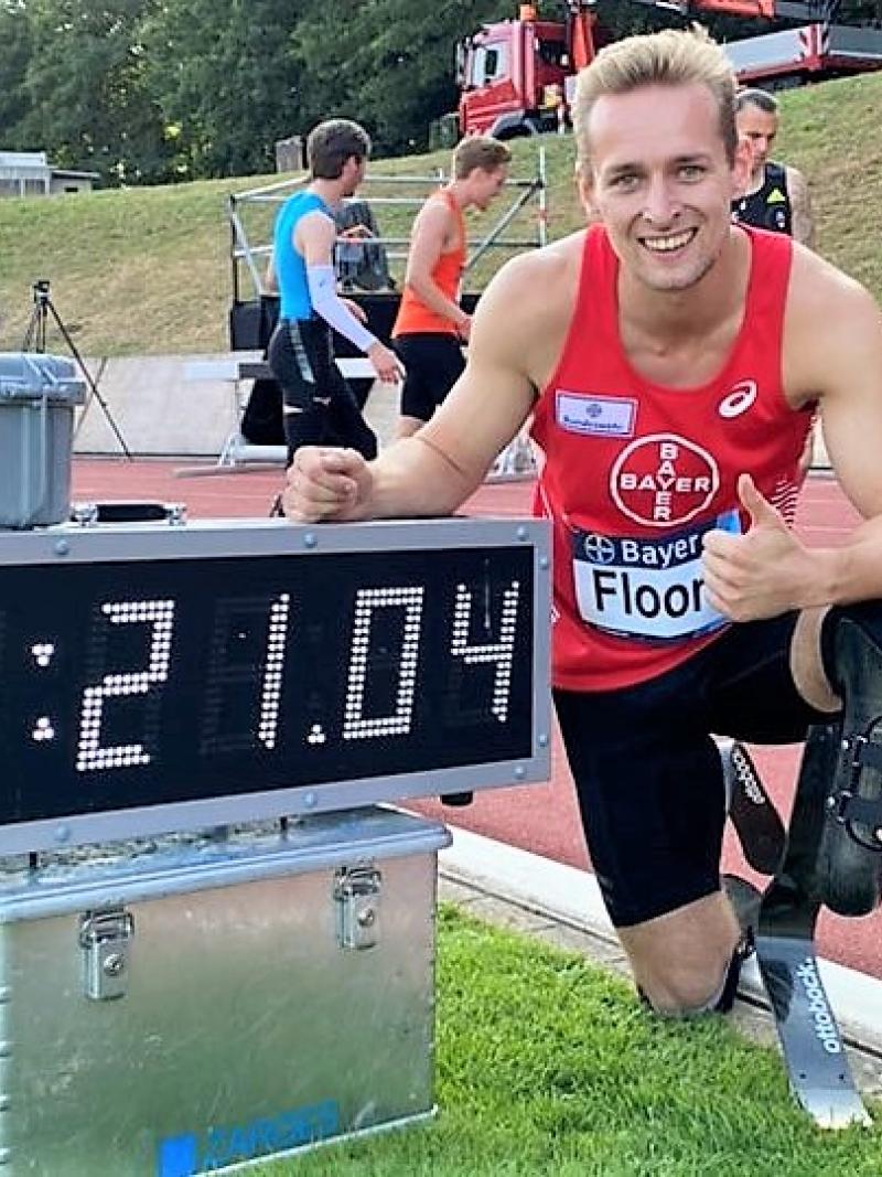 A male athlete with a prosthetic leg next to a score showing his world record