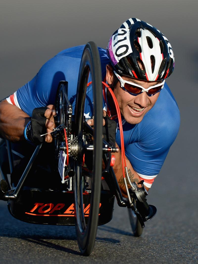 Close shot of US Para cyclist Oz Sanchez as he makes a turn on his handcycle while wearing Team USA gear