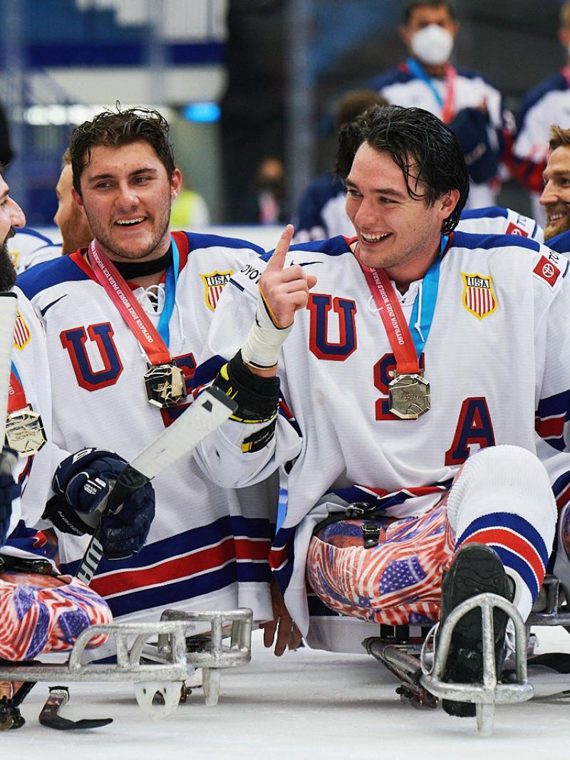 A group of USA Para ice hockey players with their gold medals on an ice rink