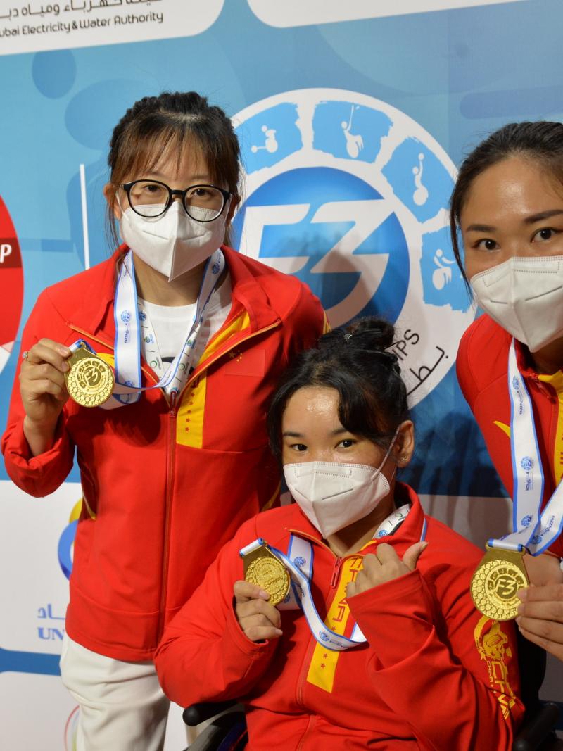 Three women with the uniform of China showing their gold medals