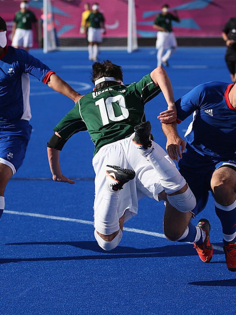 Two French defenders stop a Brazilian blind footballer