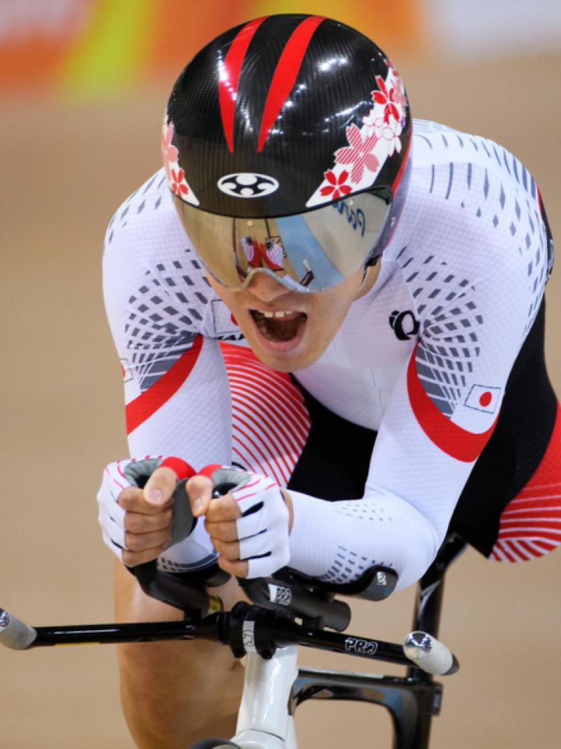 Cyclist with one leg wearing Japanese gear opens his mouth as he makes an effort during a sprint