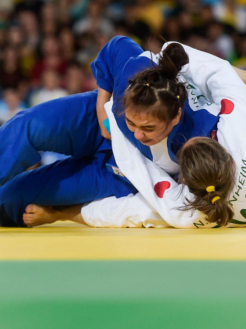 A women pins down her opponent on the judo mat