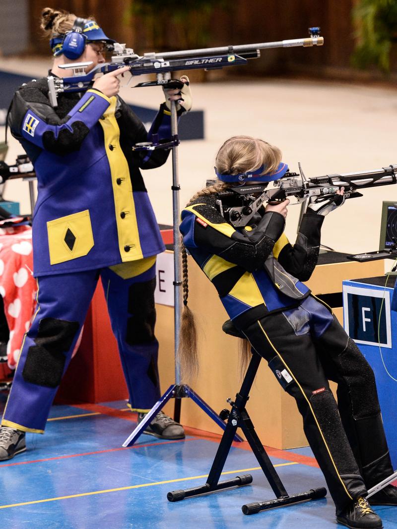 Three female athletes shooting a rifle in a range