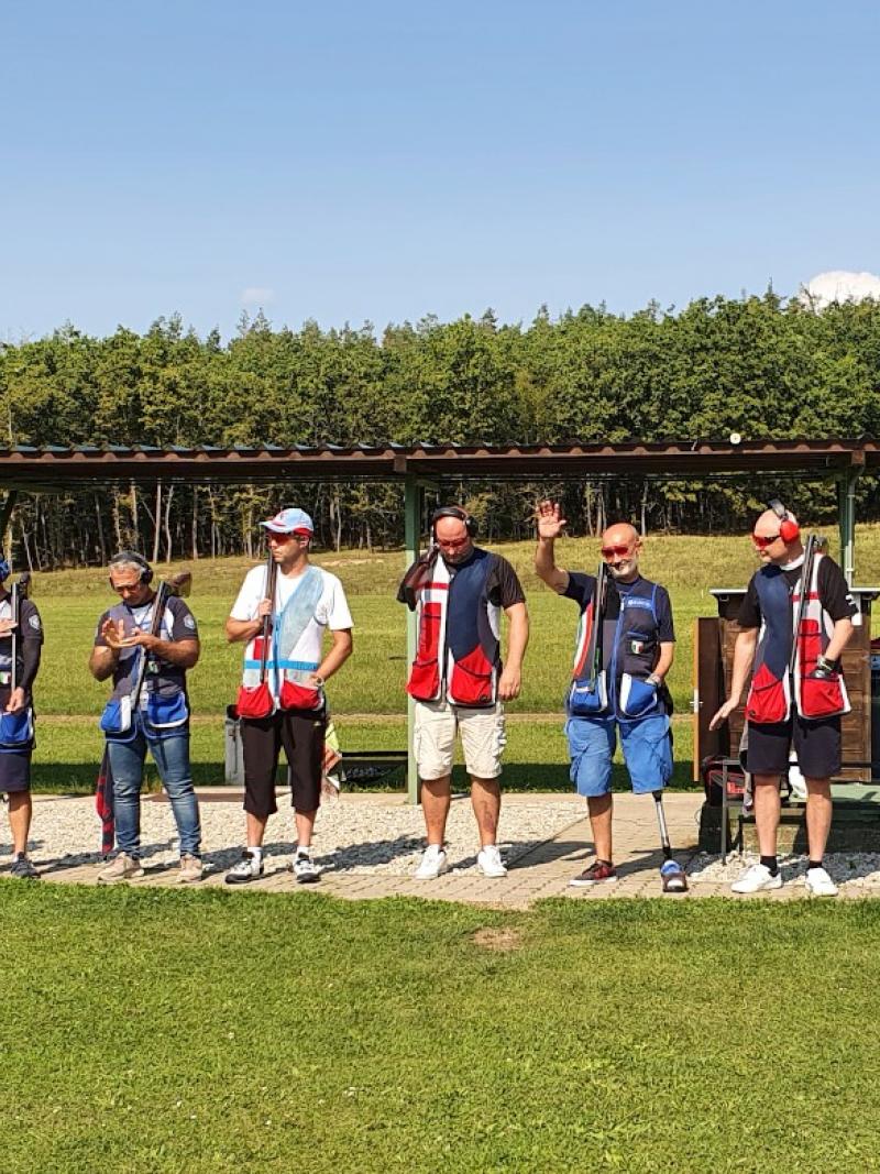 Seven men standing on a shotgun shooting range on a sunny day